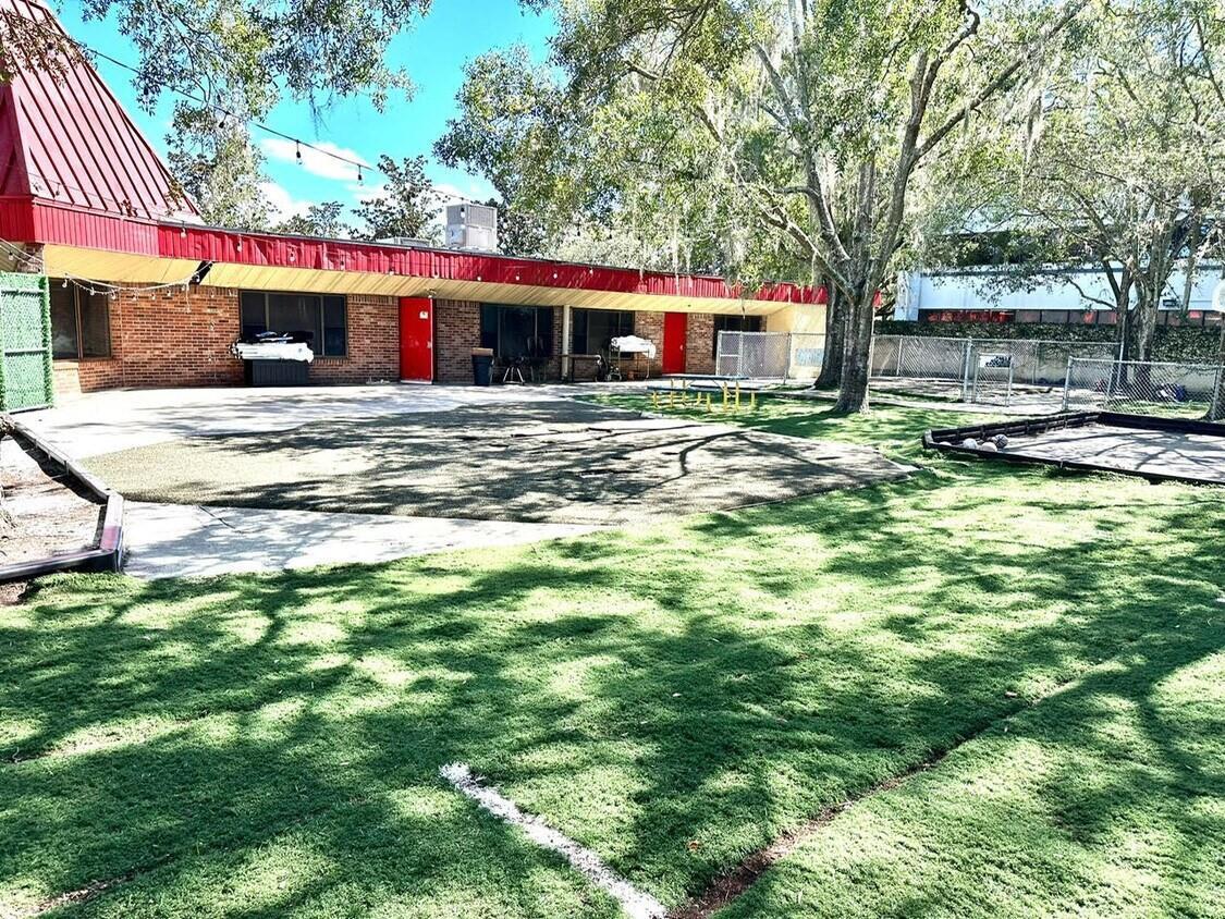 A brick building with a red roof overlooks a grassy yard and a fenced playground — 940 Winter Park Drive, FL 32707, FL