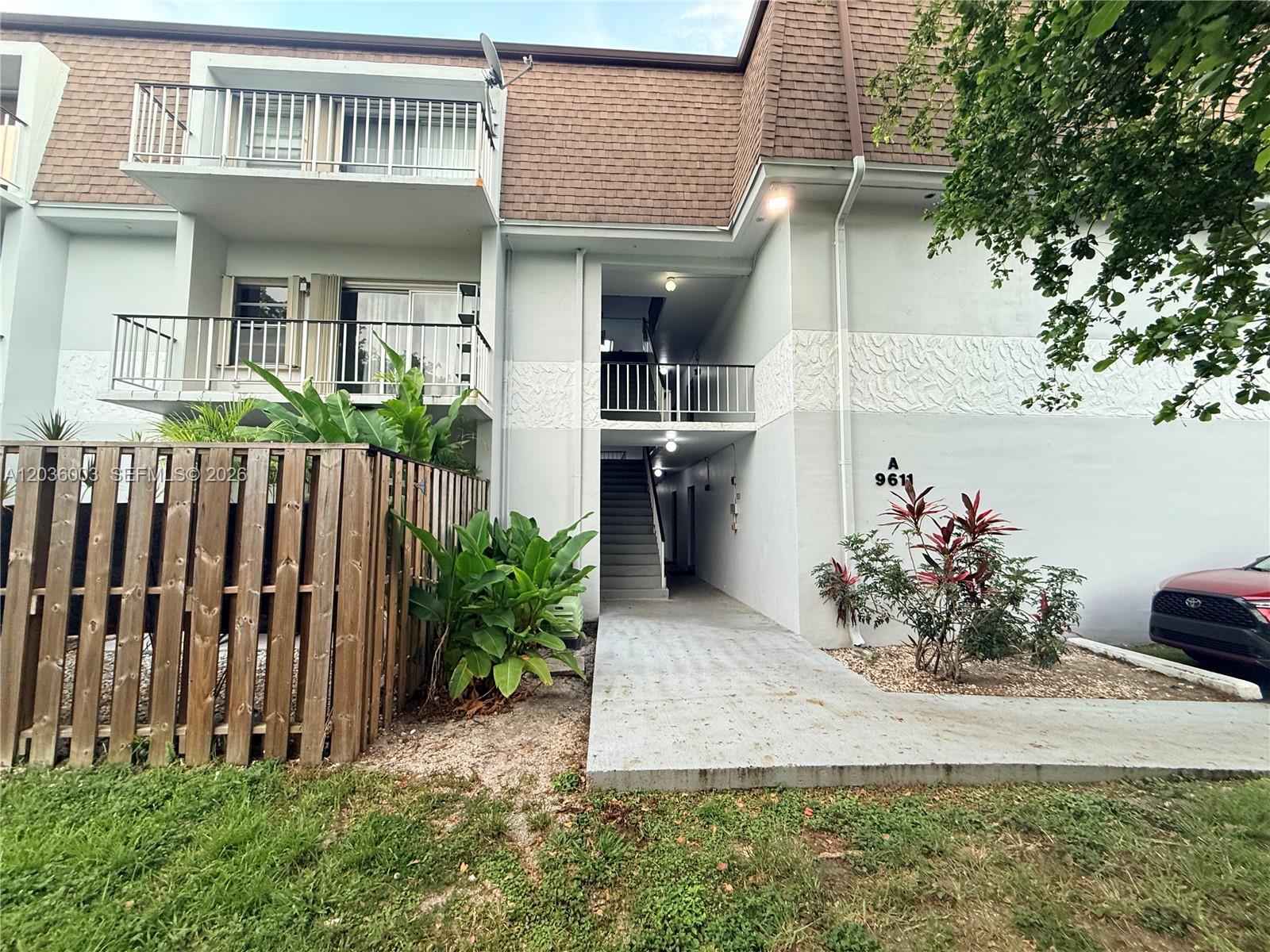 An exterior view of a multi-story apartment building with balconies and a concrete walkway — 9611 SW 77th Ave # 108A, Miami FL 33156, MIAMI, FL