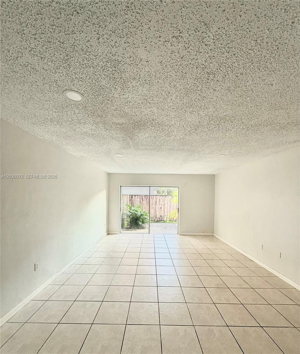 An empty room features white walls, a popcorn ceiling with recessed lighting, and tiled floors — 9611 SW 77th Ave # 108A, Miami FL 33156, MIAMI, FL