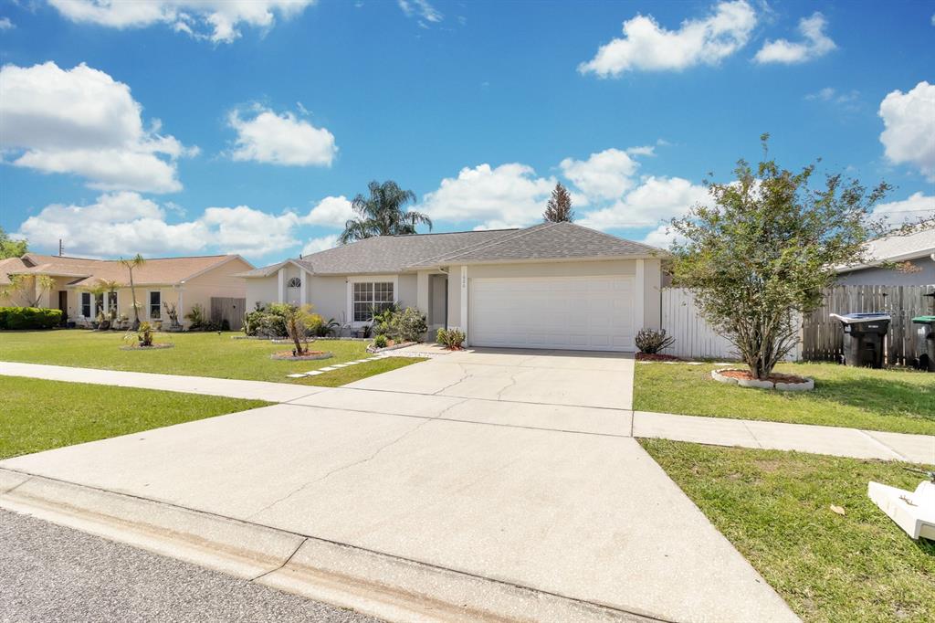 A single-story house with a beige exterior, a two-car garage, and a concrete driveway — 1620 GOLDEN POPPY COURT, ORLANDO, FL