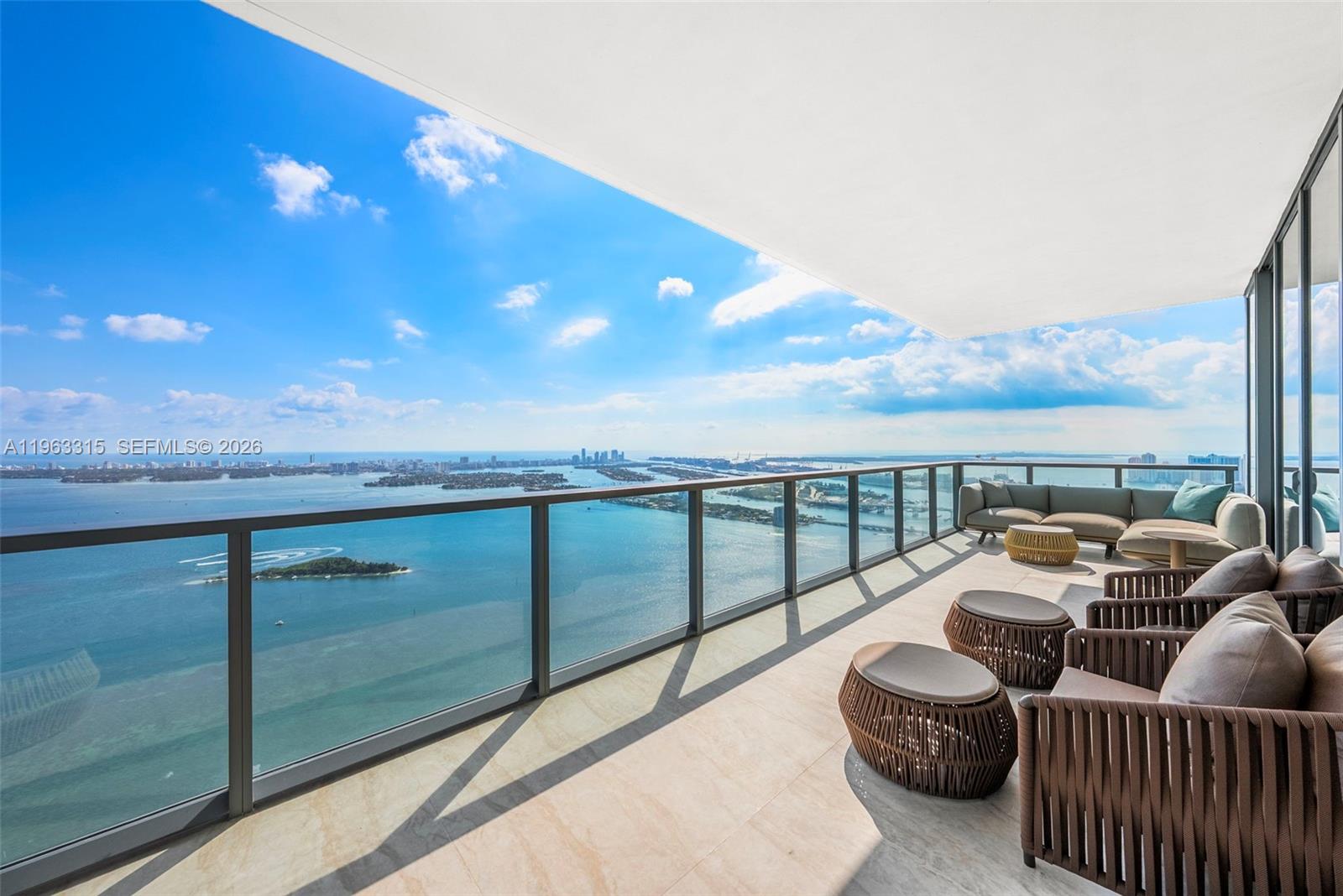 A high-rise balcony features glass railings, outdoor furniture, and a panoramic view of the ocean — 788 NE 23rd St # 5501, Miami FL 33137, MIAMI, FL