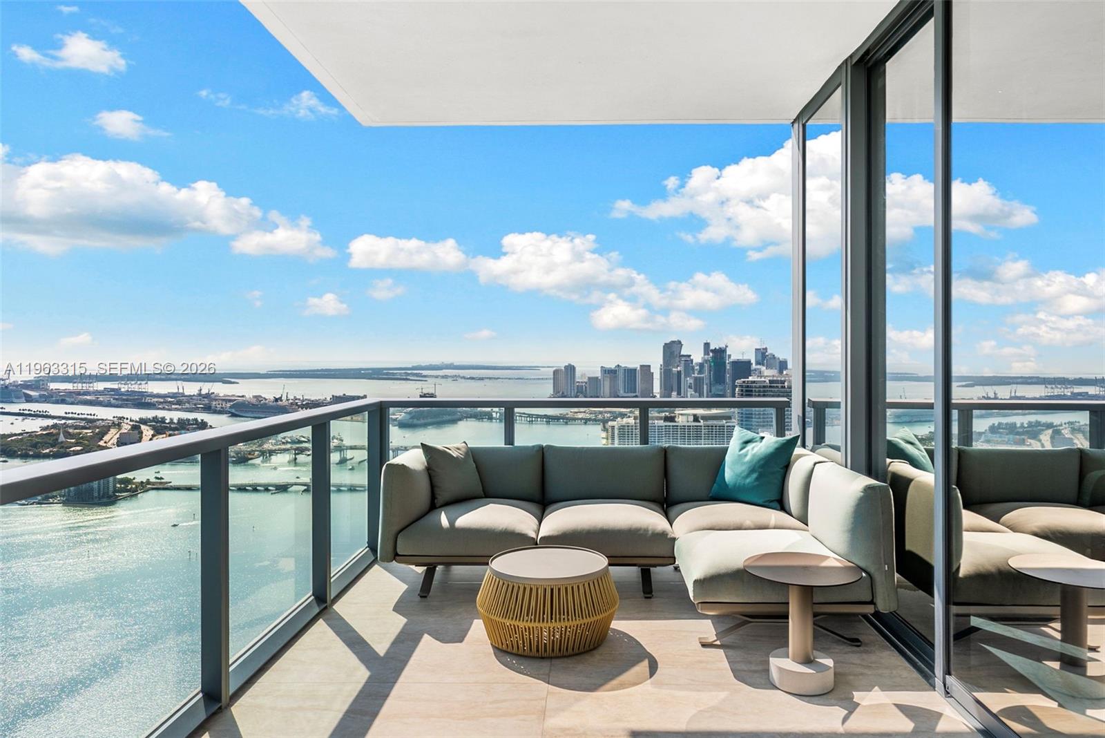 A balcony with a sectional sofa and coffee table overlooks a bay and city skyline — 788 NE 23rd St # 5501, Miami FL 33137, MIAMI, FL