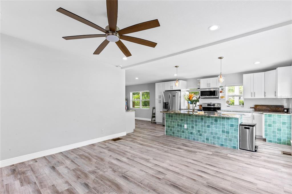 A kitchen features white cabinetry, a teal tiled island, and light wood-look flooring — 1502 MONTCALM STREET, ORLANDO, FL