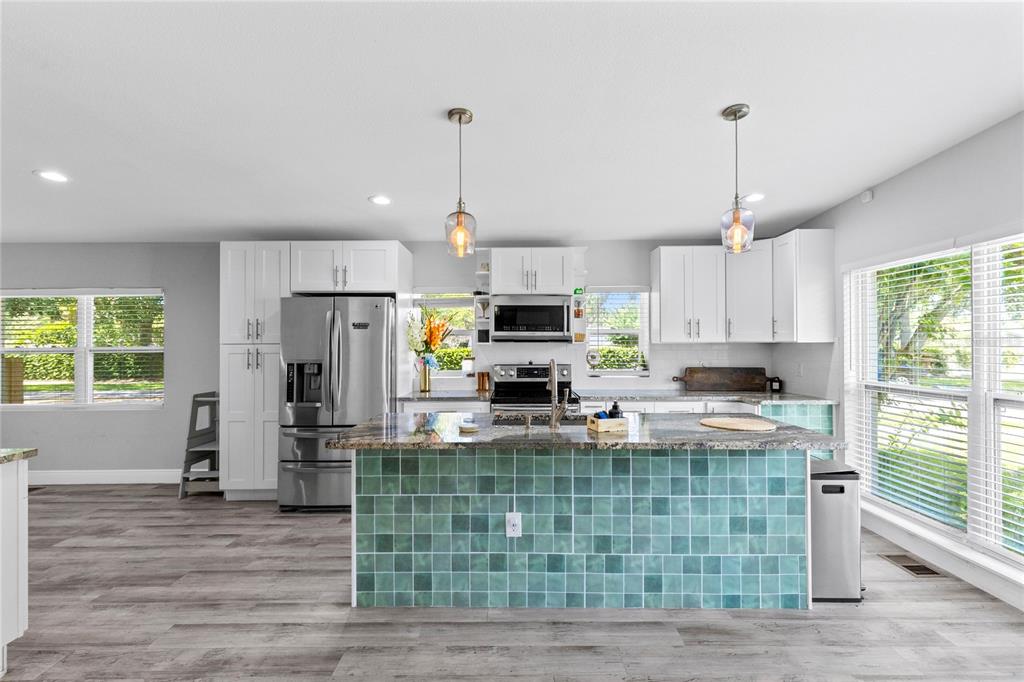 A kitchen features white cabinetry, stainless steel appliances, and a teal tiled kitchen island — 1502 MONTCALM STREET, ORLANDO, FL