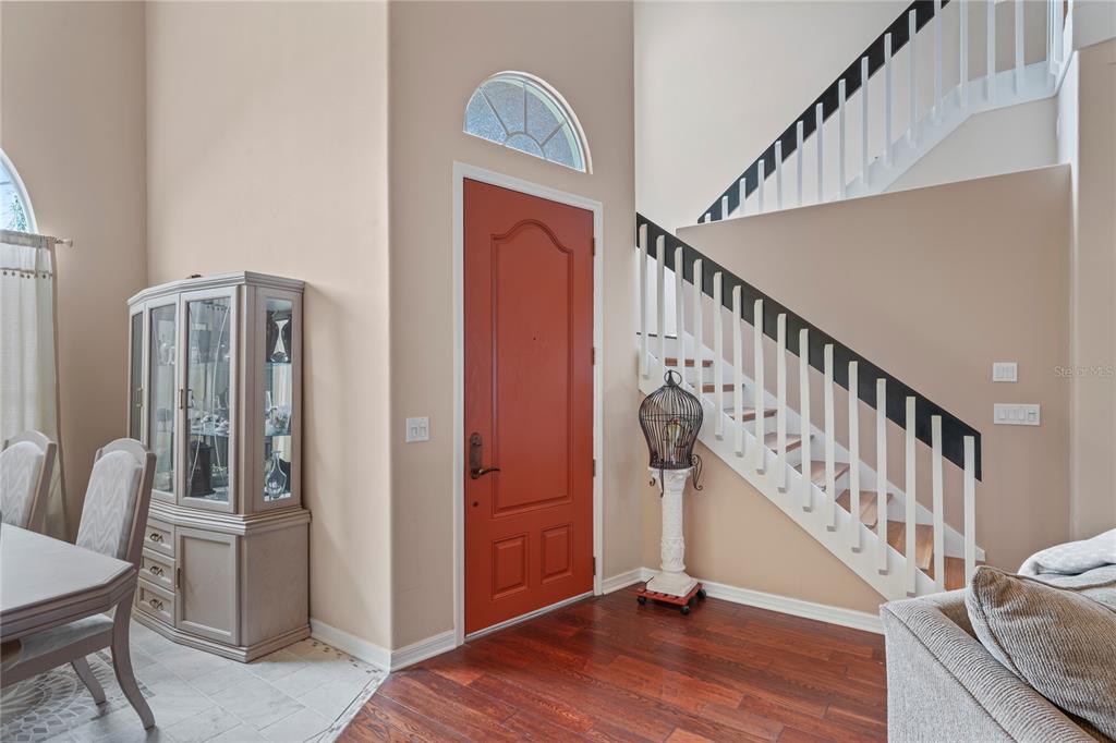 An entryway features a red door, a staircase with white railings, and a china cabinet — 277 WOOD DOVE AVENUE, TARPON SPRINGS, FL