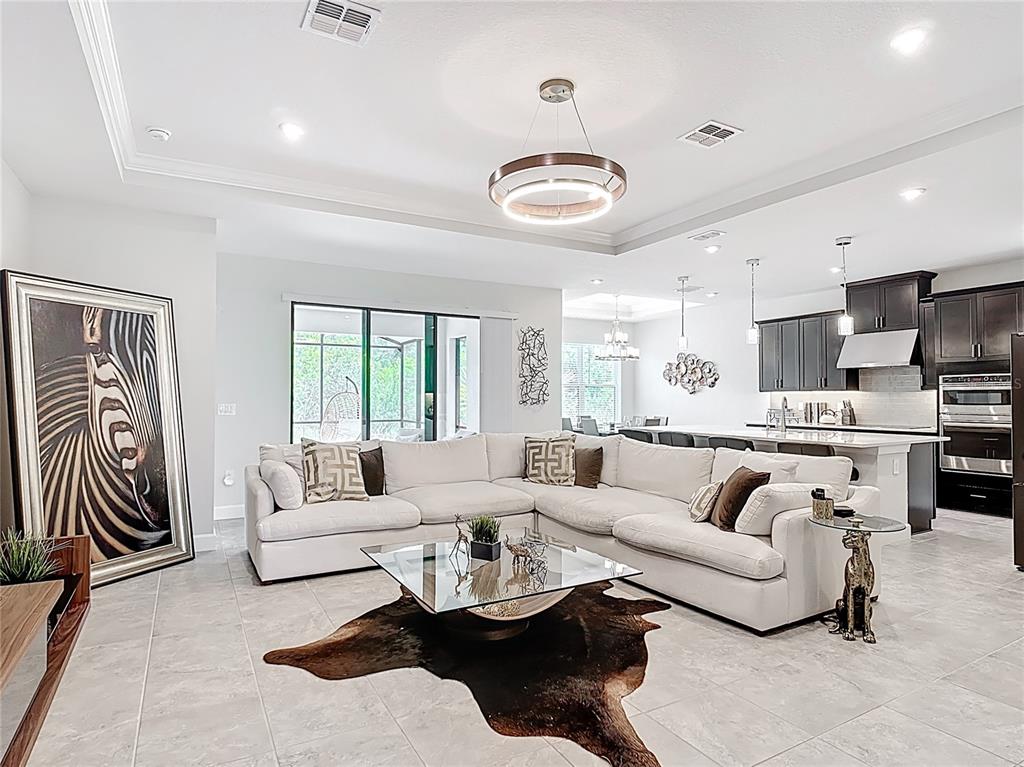 A living room features a white sectional sofa, glass coffee table, and a large zebra painting — 684 SAN AUGUSTO DRIVE, POINCIANA, FL