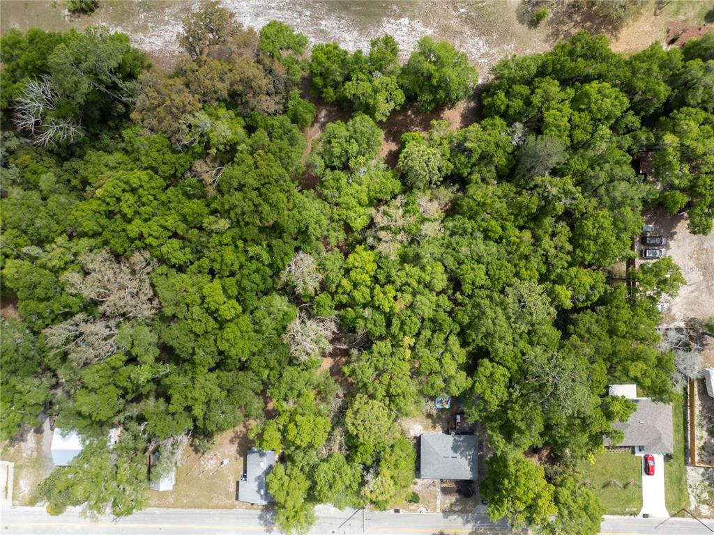An aerial view shows a wooded lot with two small houses along a paved road — E HUBBARD AVENUE, DELAND, FL