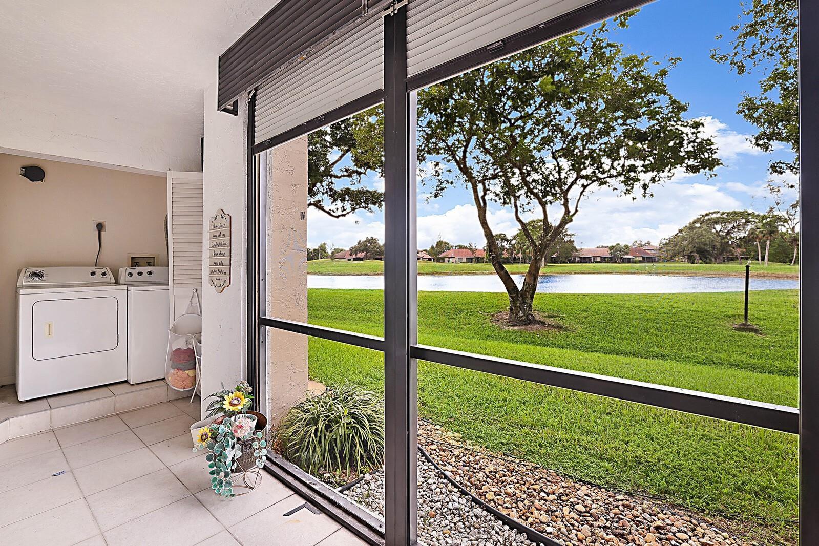 A screened-in patio features a laundry area with a washer and dryer overlooking a pond — 3485 Environ Boulevard # C106, Lauderhill FL 33319, LAUDERHILL, FL