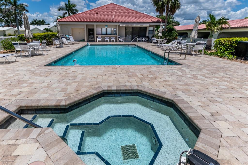 A swimming pool and hot tub are surrounded by a paved patio and clubhouse building — 2601 W MARION AVENUE UNIT 41C, PUNTA GORDA, FL