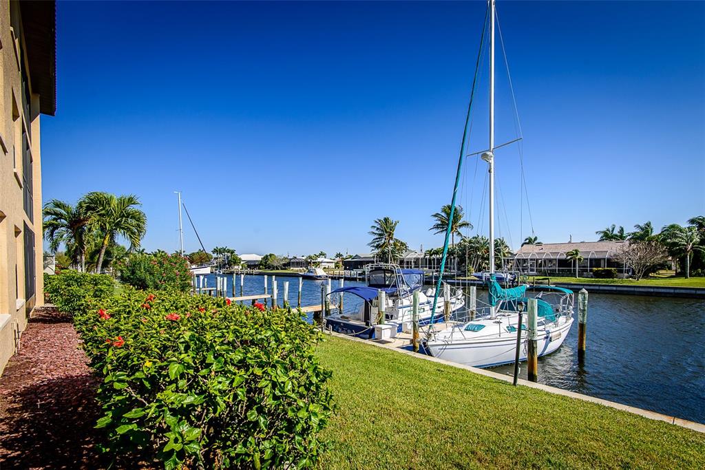A canal view featuring a sailboat and motorboat docked beside a grassy lawn and building — 2601 W MARION AVENUE UNIT 41C, PUNTA GORDA, FL