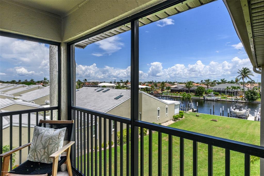 A screened-in balcony overlooks a grassy lawn, a canal with boats, and neighboring houses — 2601 W MARION AVENUE UNIT 41C, PUNTA GORDA, FL