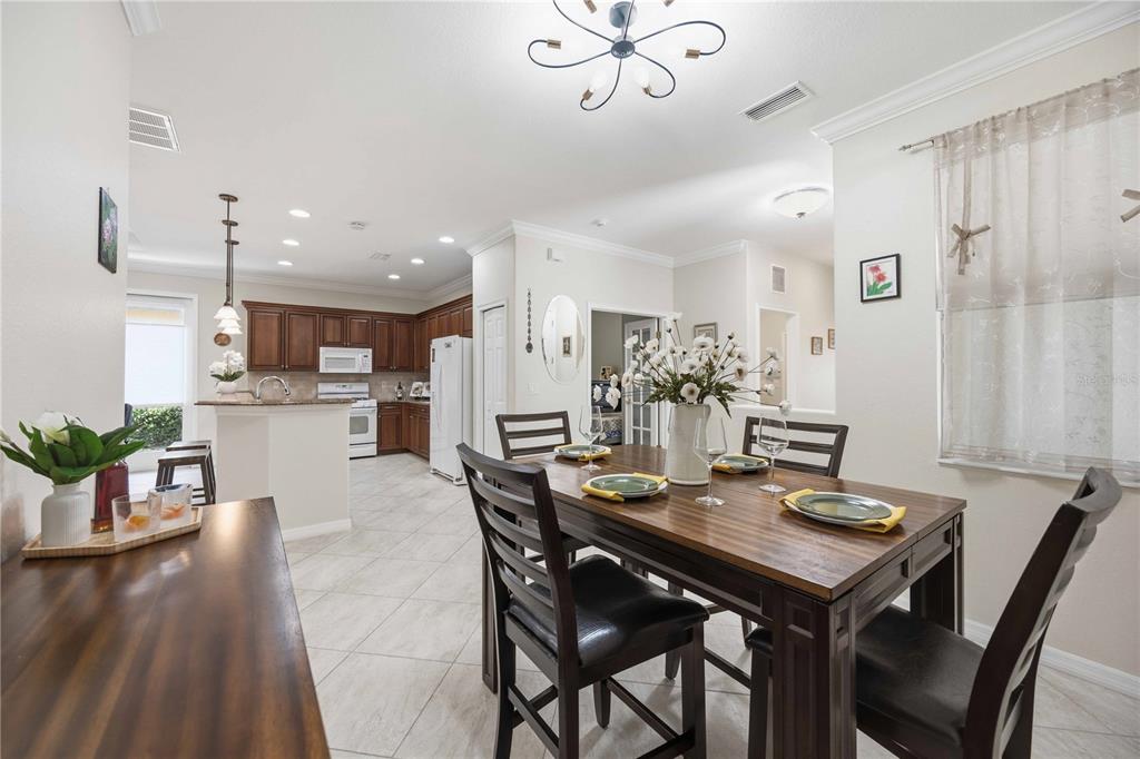 A dining area with a wooden table and chairs adjacent to an open-concept kitchen — 225 MESTRE PLACE, NORTH VENICE, FL