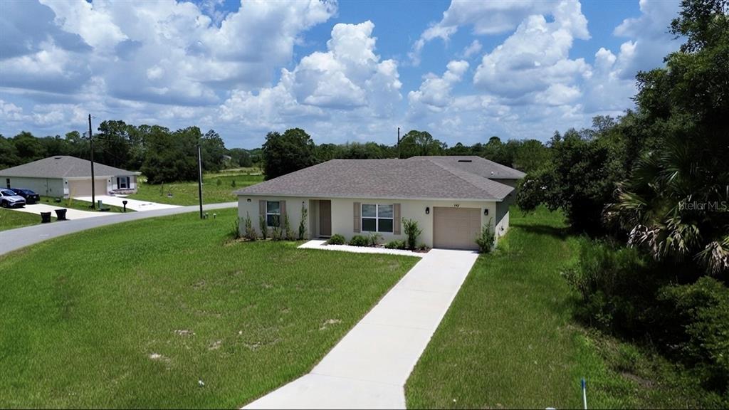 An aerial view of a single-story suburban house with a concrete driveway and grass lawn — 360 BASS COURT, KISSIMMEE, FL