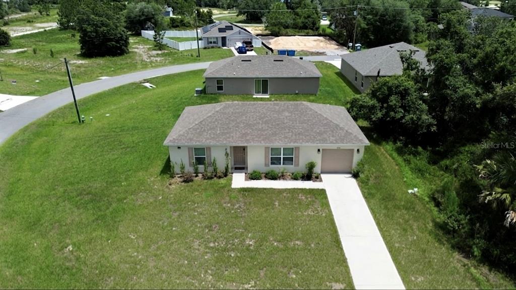 An aerial view shows a single-story house with a tan exterior and a concrete driveway — 360 BASS COURT, KISSIMMEE, FL