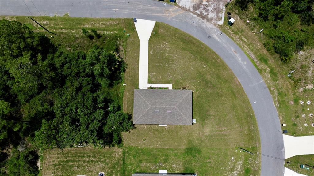 An aerial view shows a single-story house with a driveway on a grassy lot — 360 BASS COURT, KISSIMMEE, FL