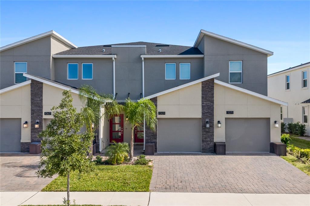A multi-unit residential building features gray stucco walls, stone accents, and paved driveways — 1069 SPLASH SHOT PLACE UNIT 1804, DAVENPORT, FL