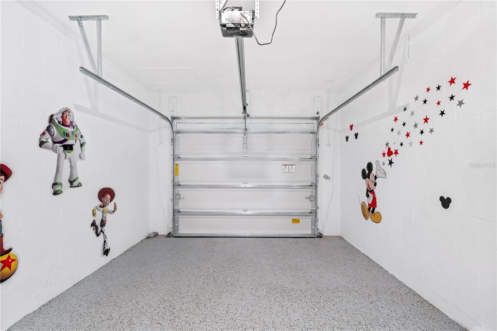 A garage with a concrete floor, white walls, and Disney-themed wall decals — 1069 SPLASH SHOT PLACE UNIT 1804, DAVENPORT, FL