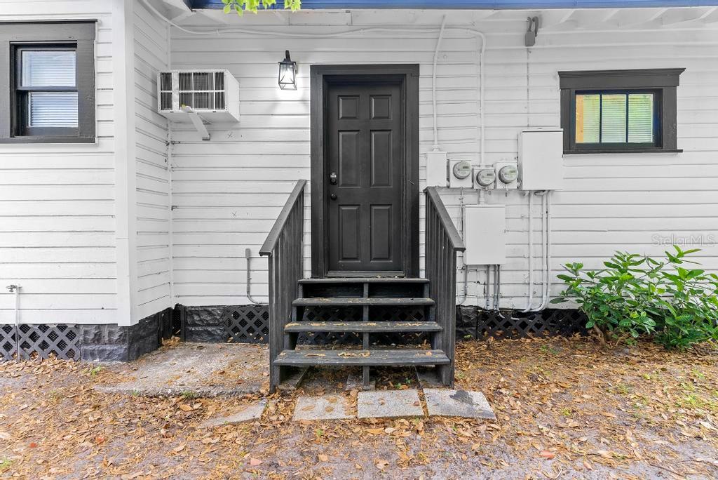 Exterior view of a white house with a black door, stairs, and window frames — 412 E HARWOOD STREET UNIT 4, ORLANDO, FL