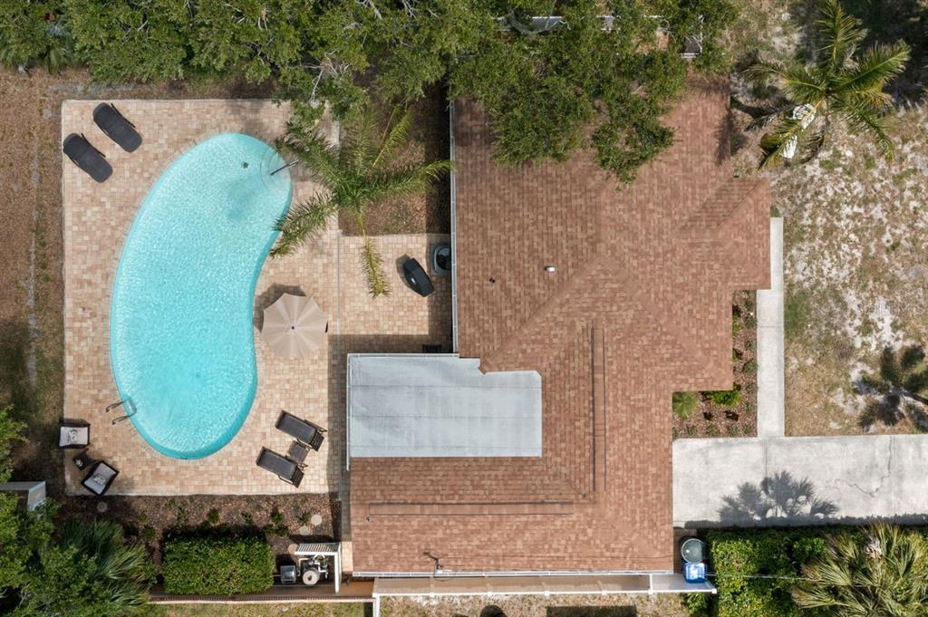 An aerial view shows a house with a brown shingled roof and a kidney-shaped pool — 1658 DOUGLAS AVENUE, DUNEDIN, FL