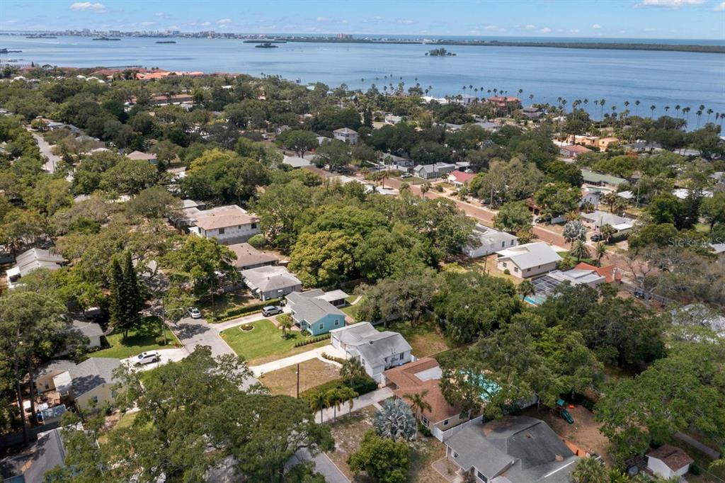 An aerial view shows a residential neighborhood with houses, trees, and a nearby body of water — 1658 DOUGLAS AVENUE, DUNEDIN, FL