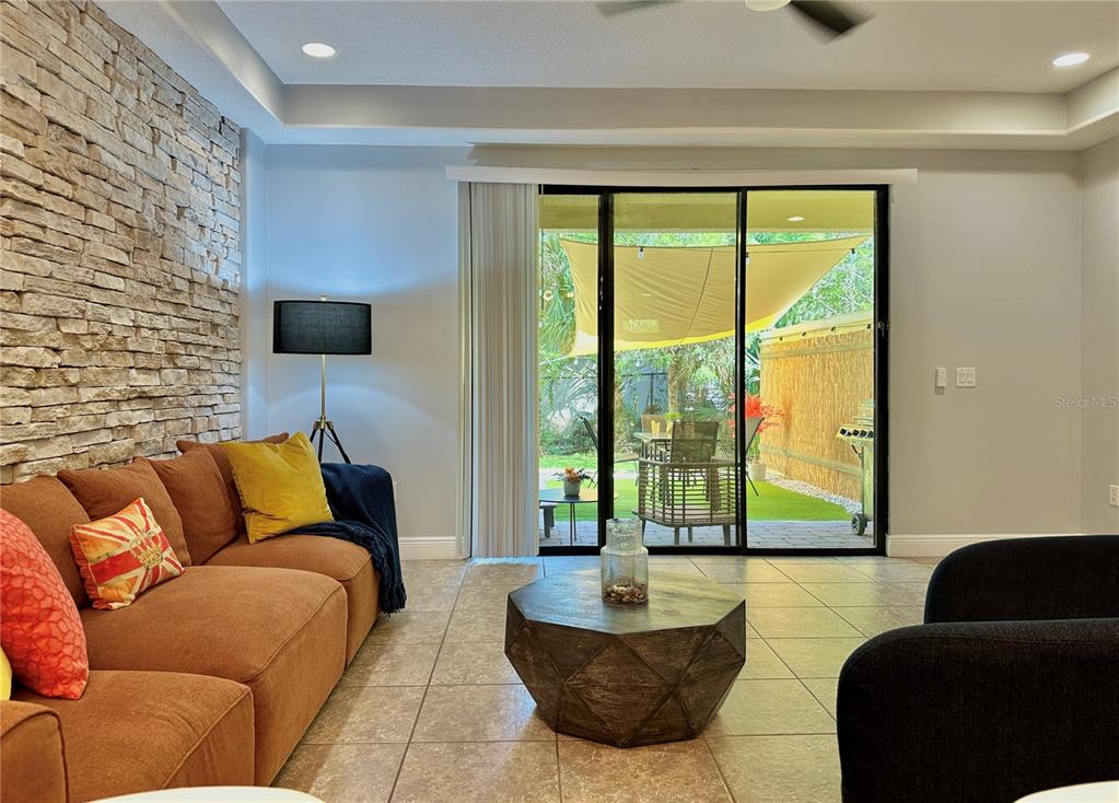 A living room features a stone accent wall, tile flooring, and a sliding glass door — 8111 ROSEVILLE BOULEVARD, DAVENPORT, FL
