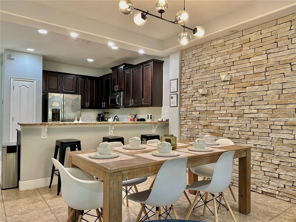 A dining area with a stone accent wall and a kitchen with dark cabinetry — 8111 ROSEVILLE BOULEVARD, DAVENPORT, FL