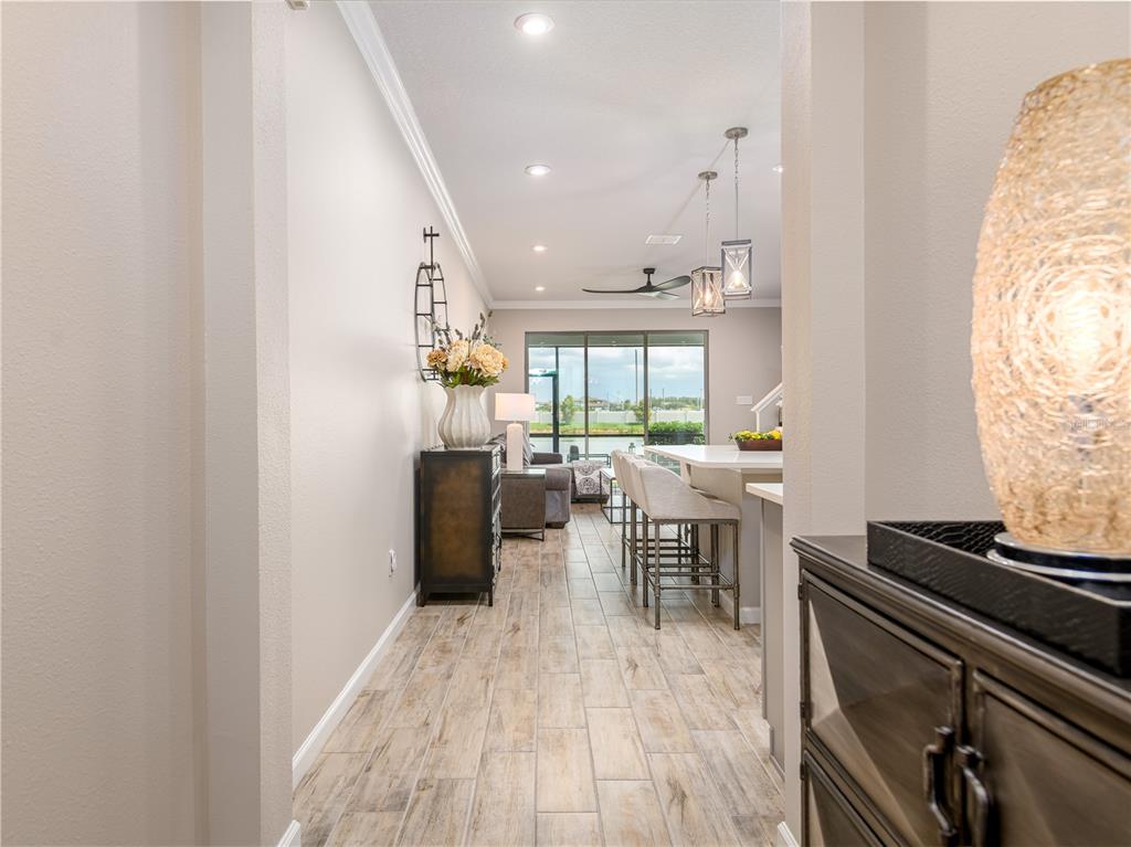 A view from a hallway into an open-concept kitchen and living area with tile floors — 19319 BLUE POND DRIVE UNIT 22, LUTZ, FL