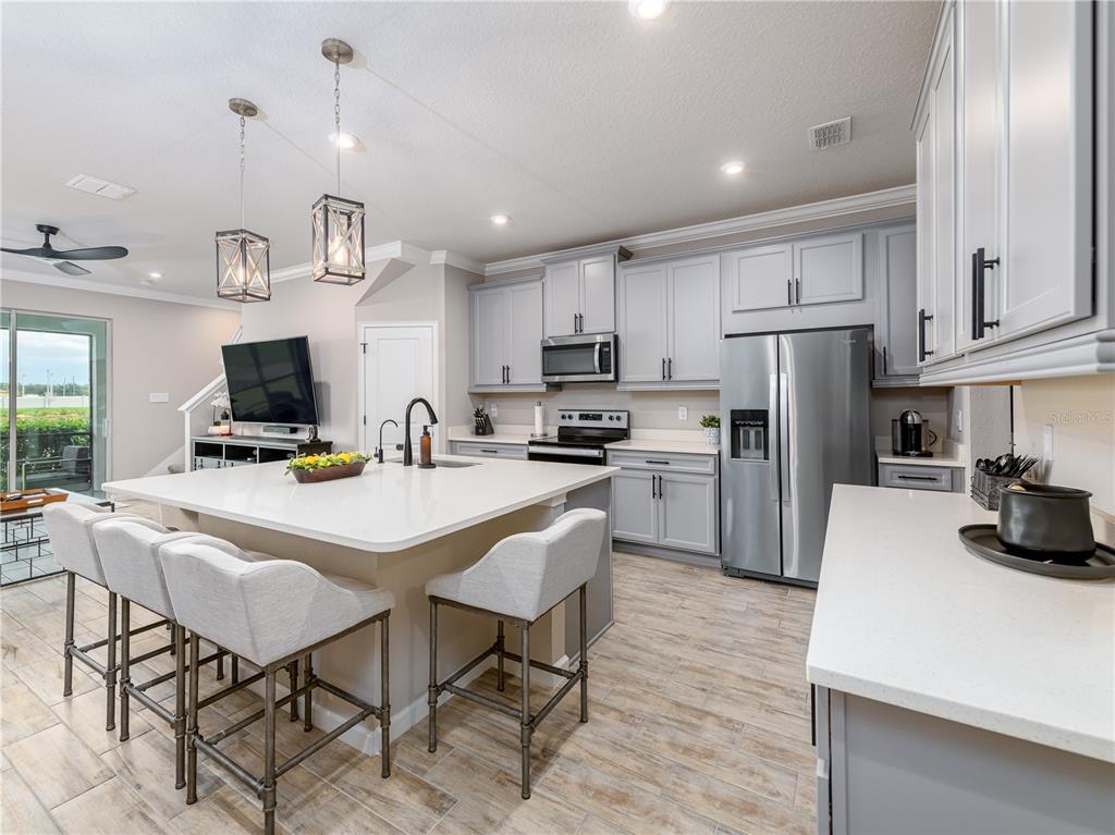 A modern kitchen features light gray cabinets, a large white island, and stainless steel appliances — 19319 BLUE POND DRIVE UNIT 22, LUTZ, FL