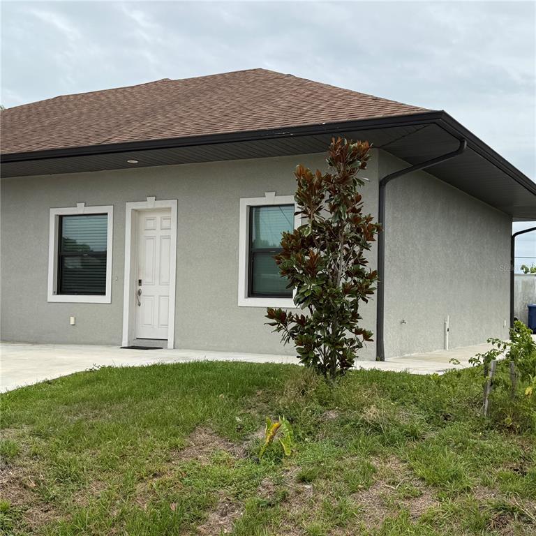 A single-story house with a gray stucco exterior, a brown roof, and a white door — 12201 ROSARO AVENUE, NORTH PORT, FL