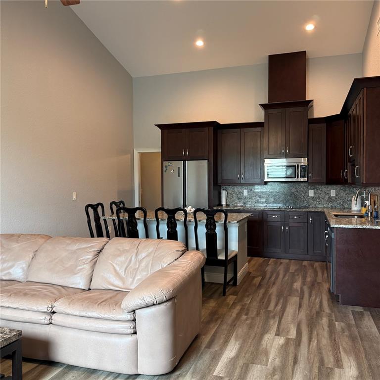 A kitchen with dark wood cabinets and granite countertops opens to a living room area — 12201 ROSARO AVENUE, NORTH PORT, FL