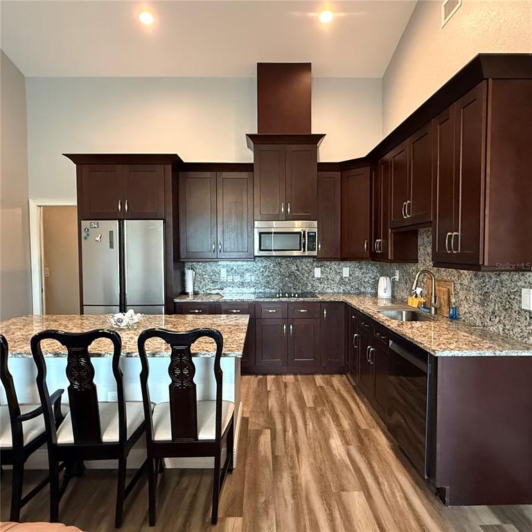 A kitchen features dark wood cabinets, granite countertops, stainless steel appliances, and a breakfast bar — 12201 ROSARO AVENUE, NORTH PORT, FL
