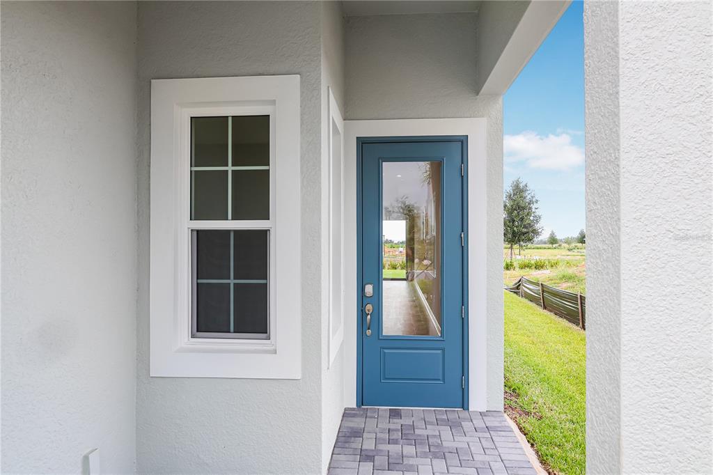 A blue glass-paneled door and a single-hung window are set in a light gray wall — 1457 SANTORINI WAY, TAVARES, FL