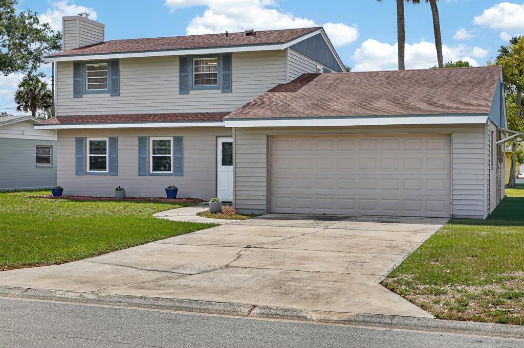 A two-story house with light-colored siding, blue shutters, a brown roof, and a concrete driveway — 1238 SUWANEE ROAD, DAYTONA BEACH, FL