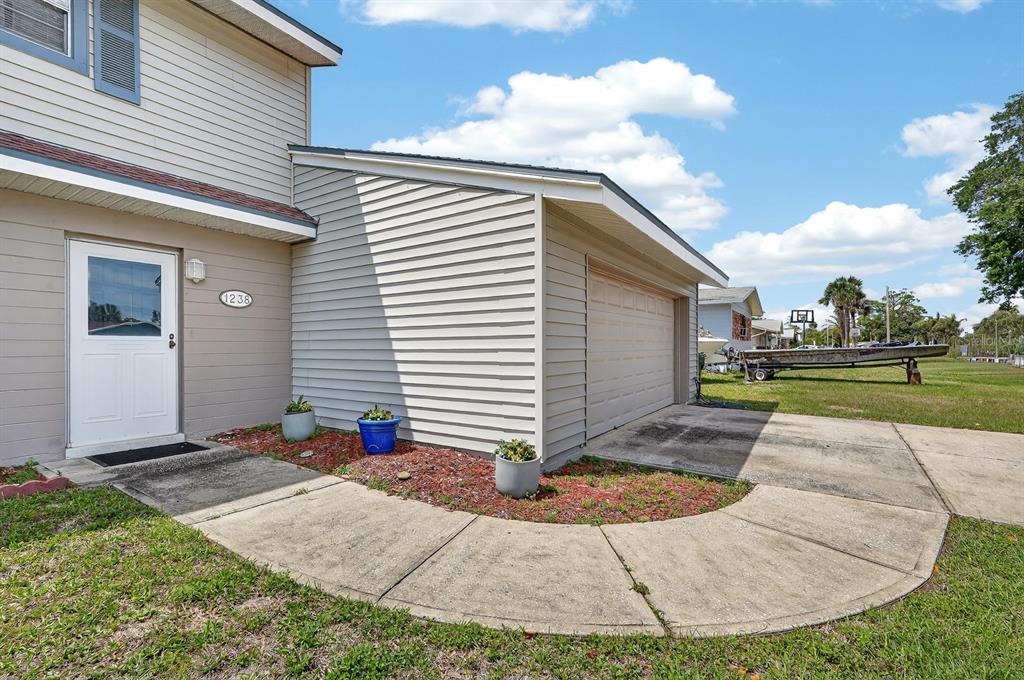A light-colored house exterior features a white front door, a garage, and a curved walkway — 1238 SUWANEE ROAD, DAYTONA BEACH, FL