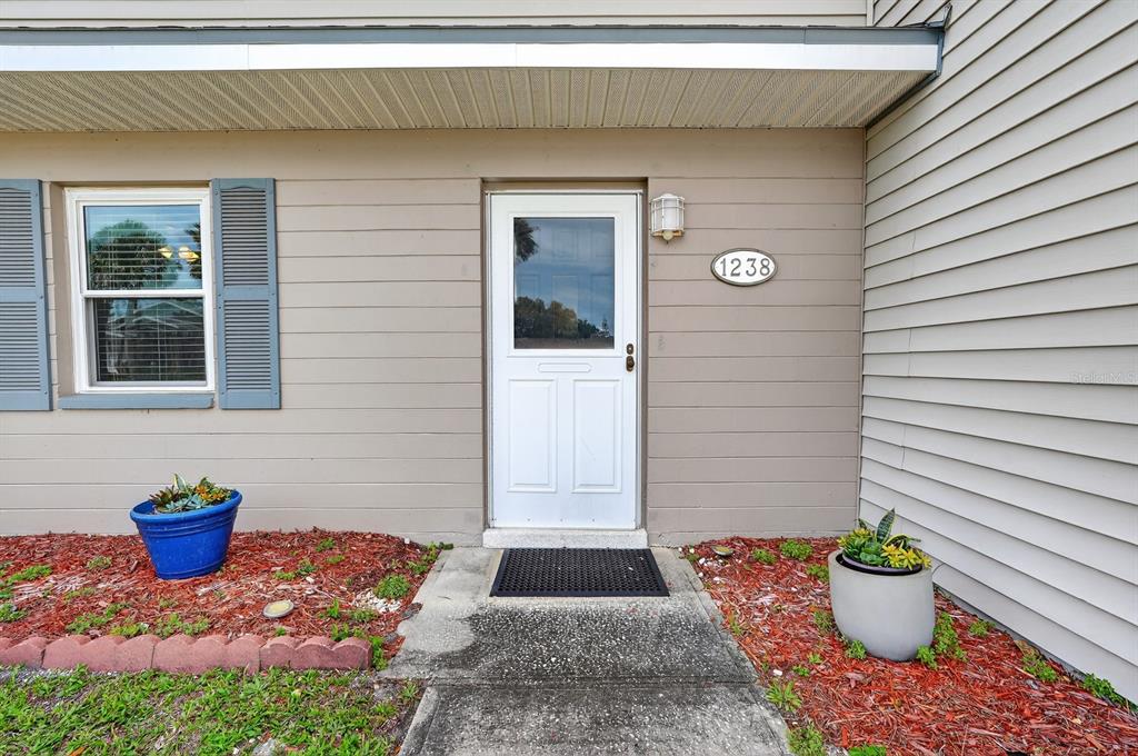 The exterior of a home features a white front door, a house number, and planters — 1238 SUWANEE ROAD, DAYTONA BEACH, FL