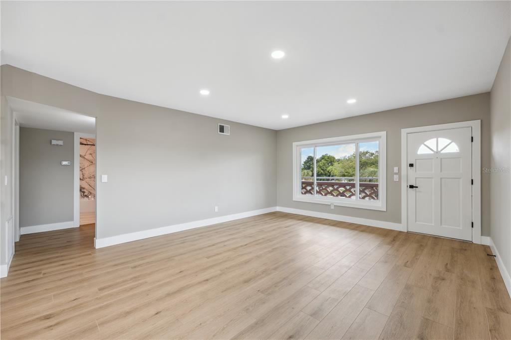 An empty room features light wood-look flooring, gray walls, recessed lighting, and a white door — 2072 AUSTRALIA WAY W UNIT 42, CLEARWATER, FL