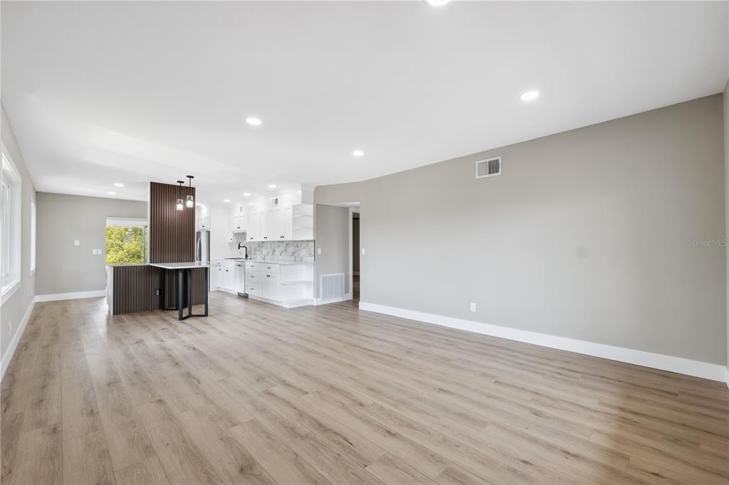An open-concept kitchen and living area features light wood flooring and white cabinetry — 2072 AUSTRALIA WAY W UNIT 42, CLEARWATER, FL