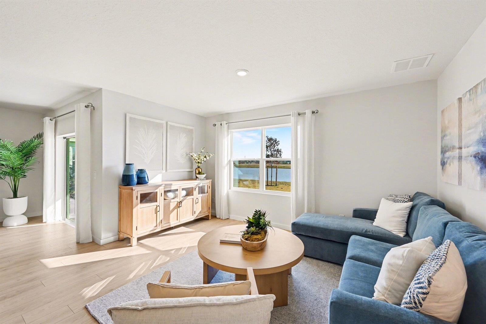 A living room features a blue sectional sofa, a wooden coffee table, and a lake view — 9069 Venetian Square, Vero Beach FL 32966, VERO BEACH, FL