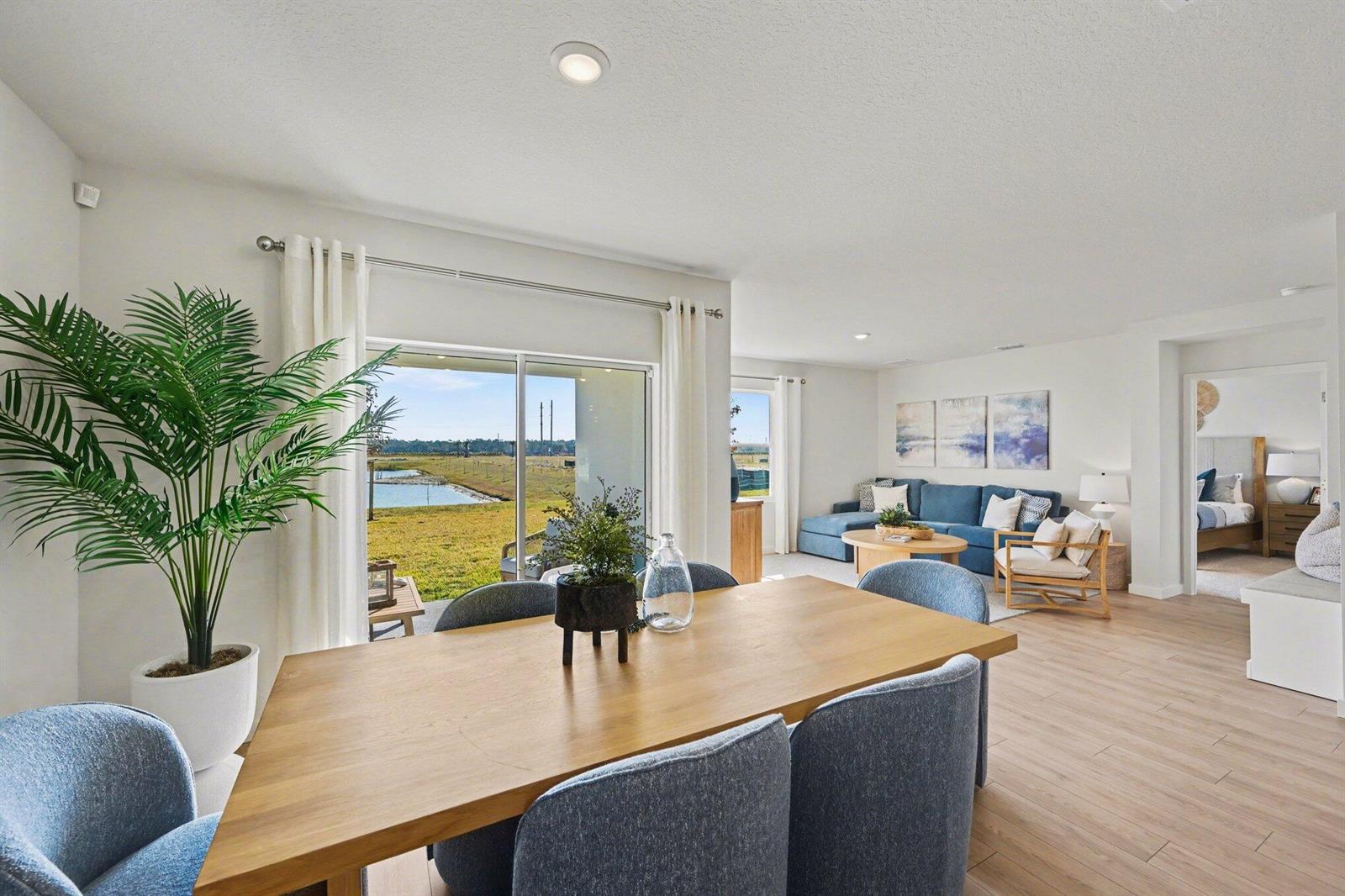 A dining area with a wooden table opens to a living room and a backyard view — 9069 Venetian Square, Vero Beach FL 32966, VERO BEACH, FL