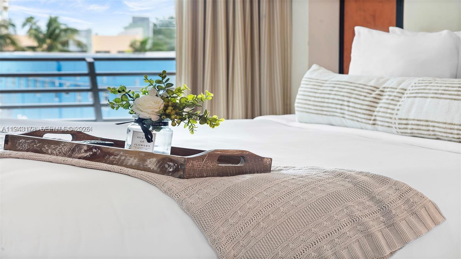 A wooden tray with a flower vase sits on a bed in a bedroom — 1437 Collins Ave # 327, Miami Beach FL 33139, MIAMI BEACH, FL