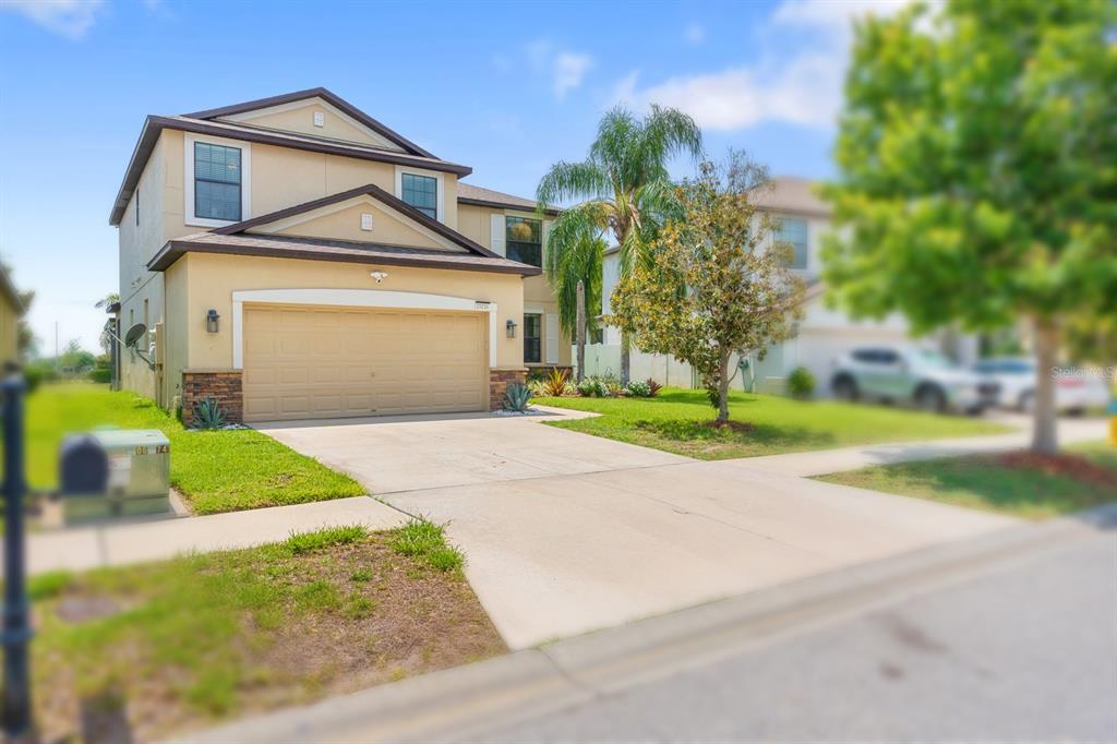 A two-story suburban house with a tan stucco exterior and a two-car garage — 13216 WELLINGTON HILLS DRIVE, RIVERVIEW, FL