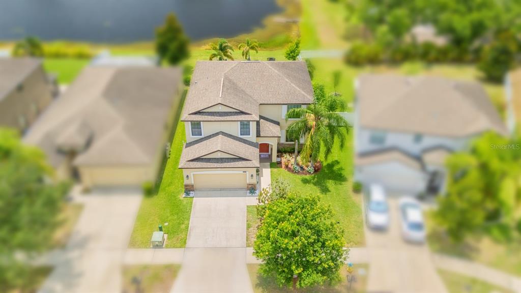 An aerial view shows a two-story suburban house with a tan exterior and a driveway — 13216 WELLINGTON HILLS DRIVE, RIVERVIEW, FL