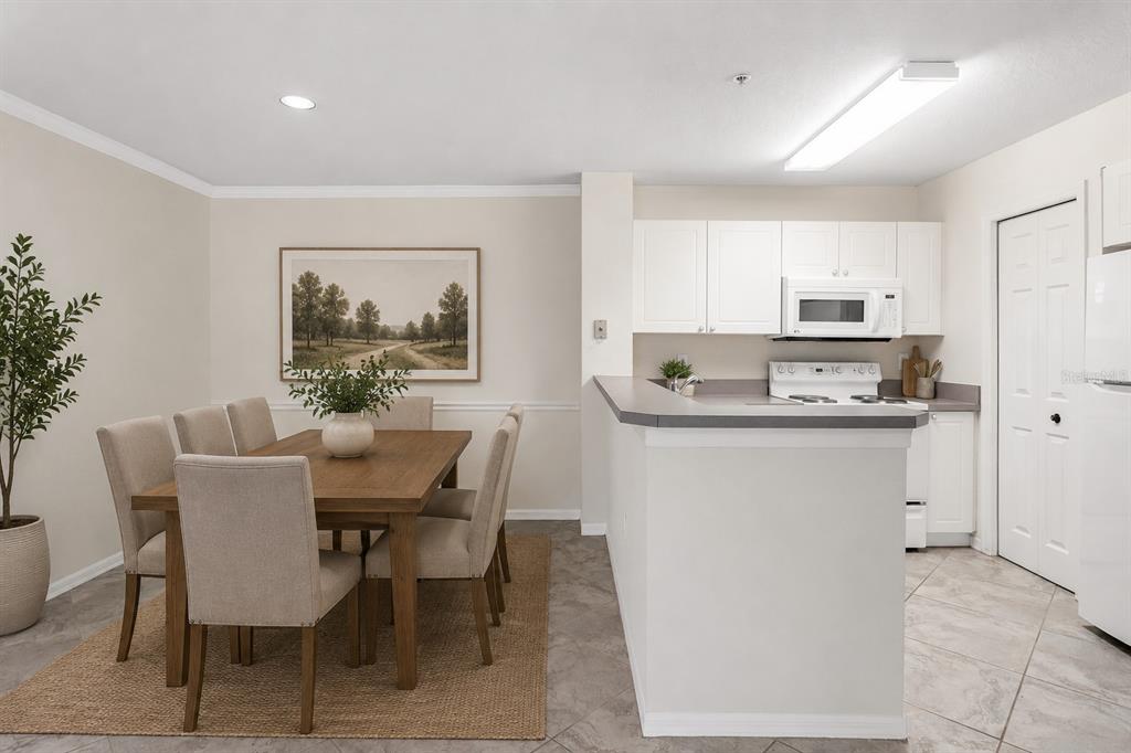 A dining area with a wooden table and chairs sits adjacent to a white kitchen — 18108 PEREGRINES PERCH PLACE UNIT 7110, LUTZ, FL