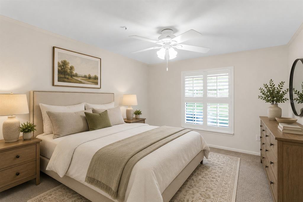 A bedroom features a bed with neutral bedding, wooden nightstands, a dresser, and a ceiling fan — 18108 PEREGRINES PERCH PLACE UNIT 7110, LUTZ, FL