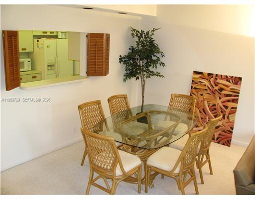 A dining room features a glass-topped rattan table, six chairs, and a kitchen pass-through window — 181 Crandon Blvd # 308, Key Biscayne FL 33149, KEY BISCAYNE, FL