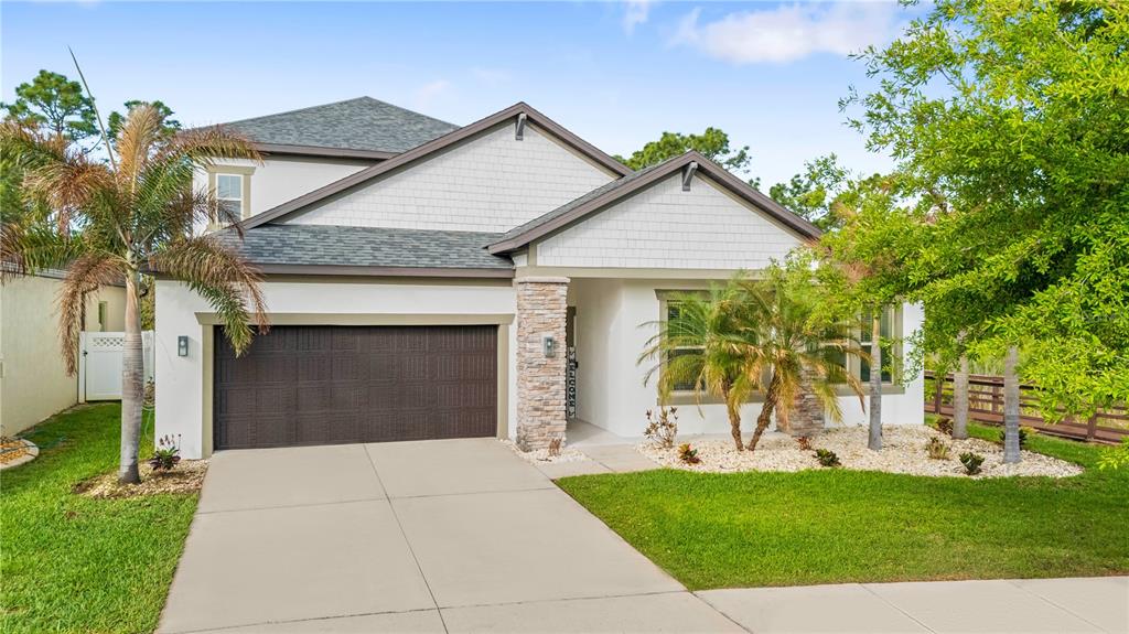 A two-story suburban house with a brown garage door, stone accents, and a palm tree — 11814 CROSS VINE DRIVE, RIVERVIEW, FL