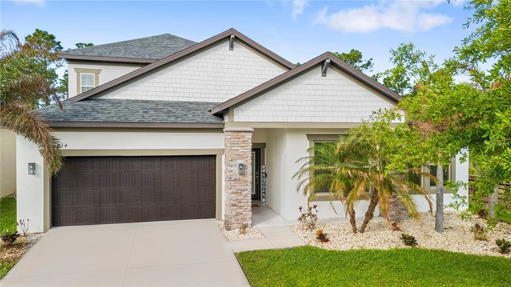 A two-story house features a brown garage, white siding, and a stone-accented entryway — 11814 CROSS VINE DRIVE, RIVERVIEW, FL