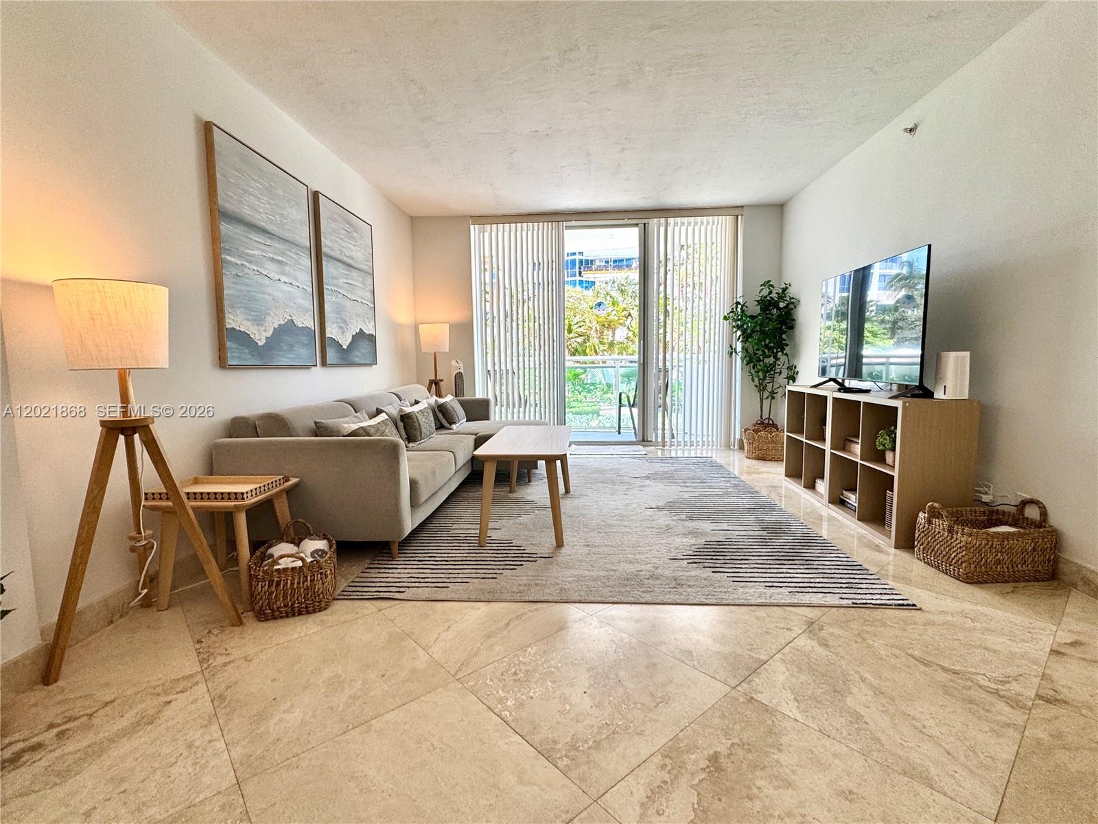 A living room features a gray sectional sofa, a television stand, and tile flooring — 3001 S Ocean Dr # 119, Hollywood FL 33019, HOLLYWOOD, FL