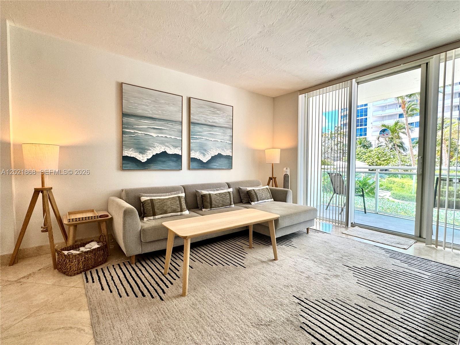 A living room features a gray sectional sofa, a wooden coffee table, and a balcony view — 3001 S Ocean Dr # 119, Hollywood FL 33019, HOLLYWOOD, FL