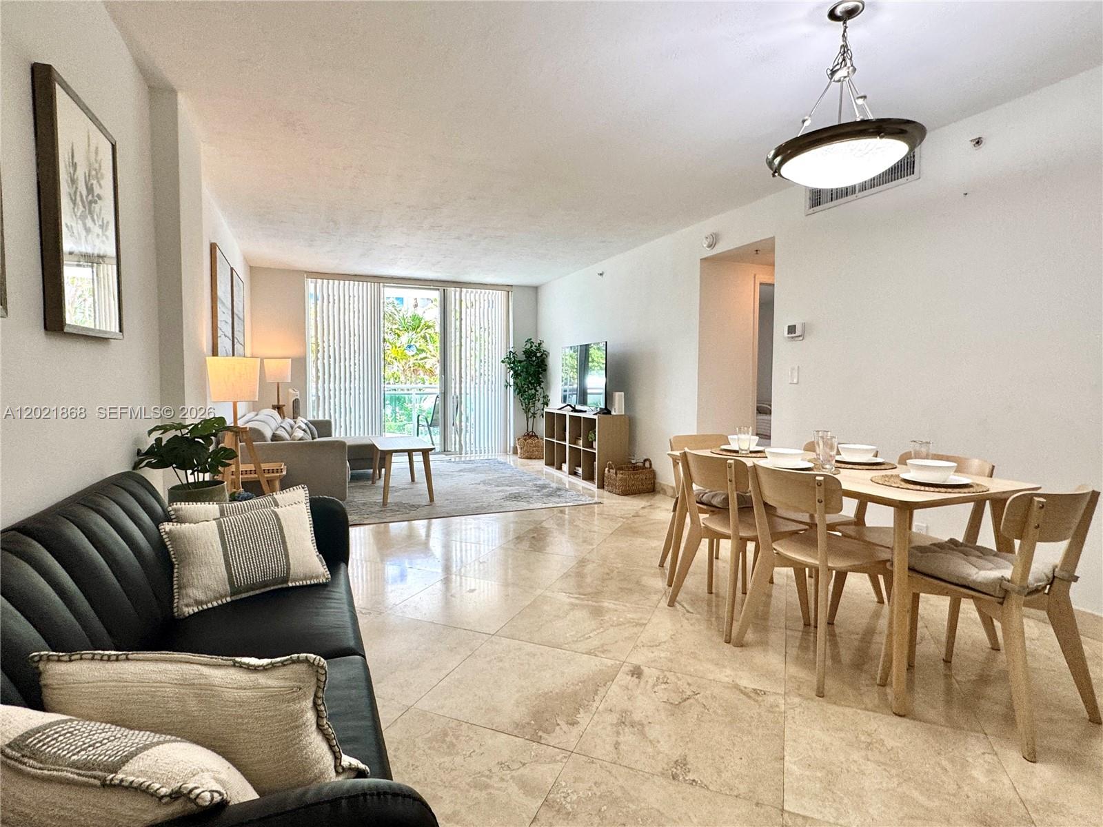 A living and dining area features tile floors, a black sofa, and a glass balcony door — 3001 S Ocean Dr # 119, Hollywood FL 33019, HOLLYWOOD, FL